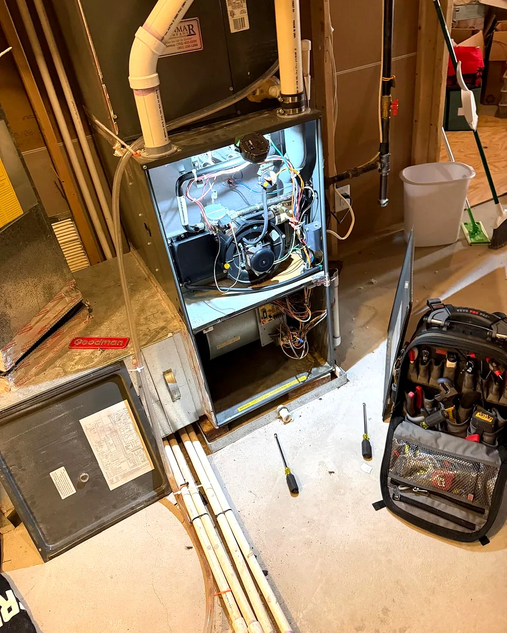 Technician servicing an open gas furnace during a heating repair