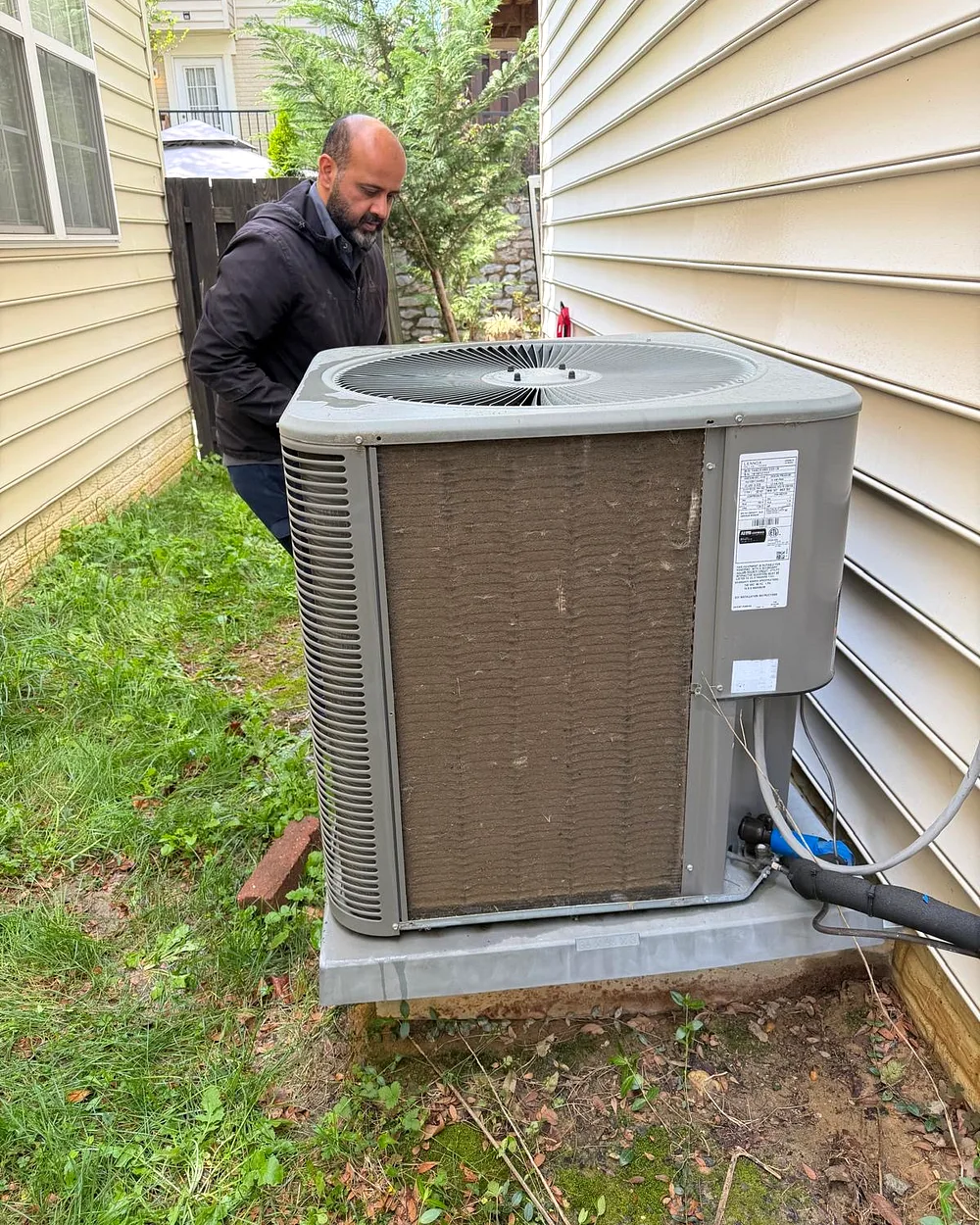 Coolvibe technician inspecting an outdoor AC unit on a service call